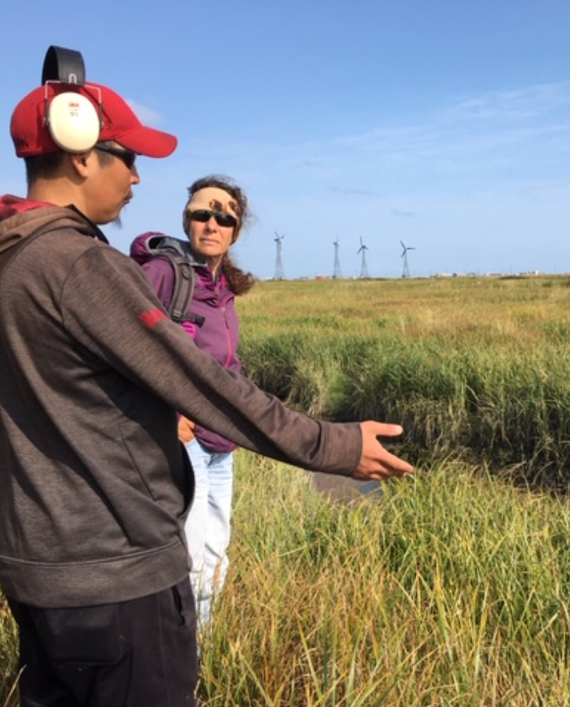 Man with headphones talks to woman in a field of tall grass