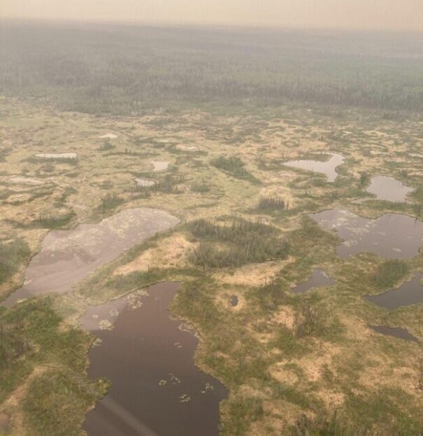 Photo of green, yellow, brown permafrost bogs shrouded in haze from a nearby fire.